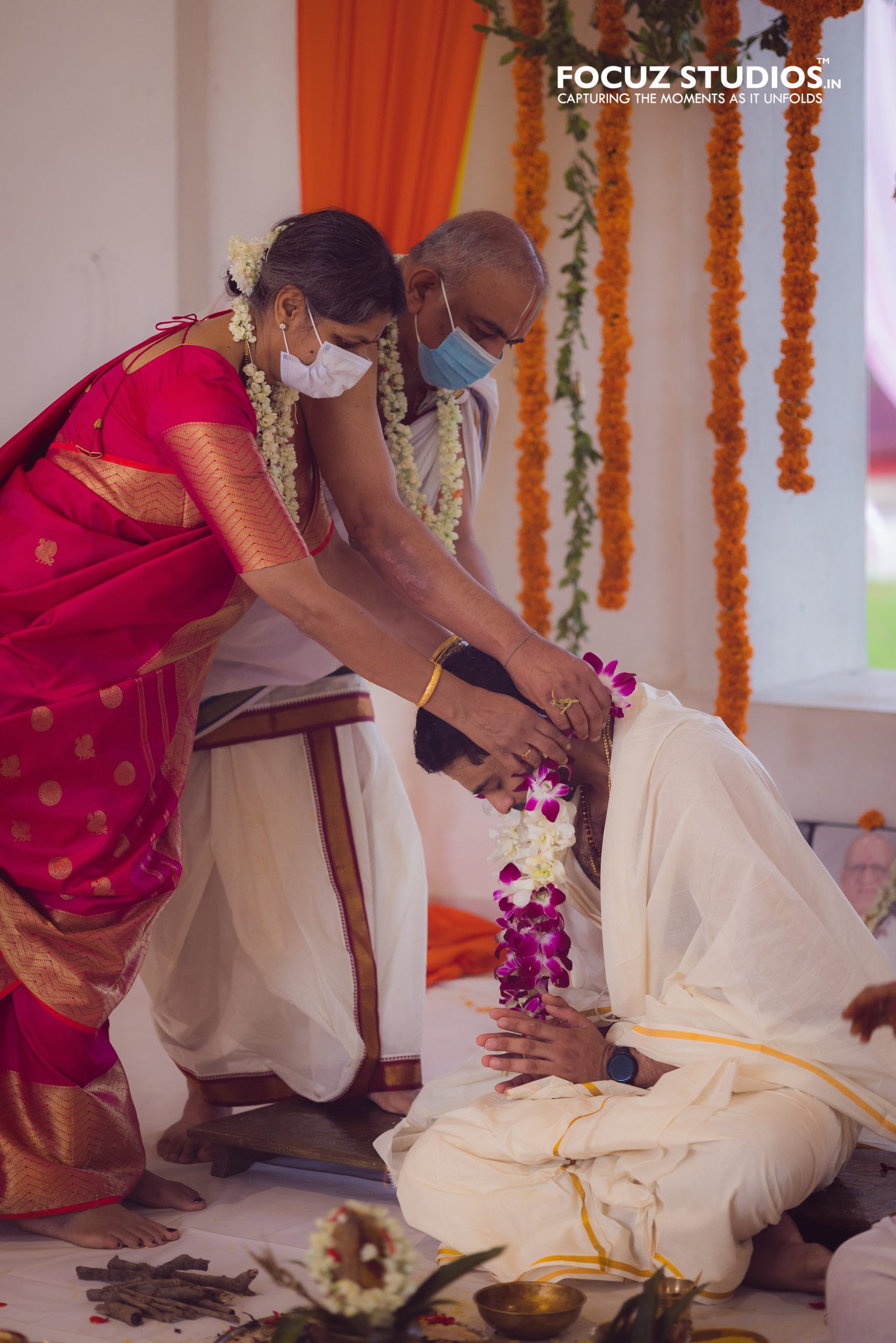 Parents placing a flower garland on the groom